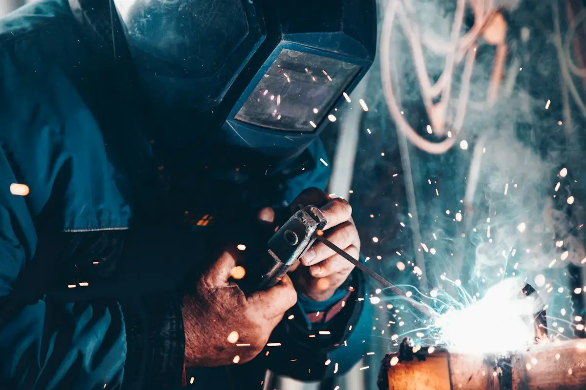 Engineer welding a metal component in an industrial workshop